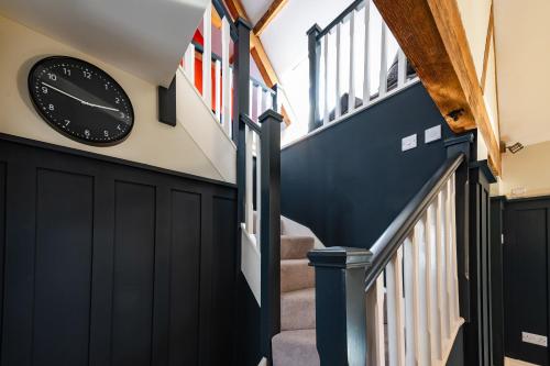 a clock on the wall of a hallway with stairs at Luxury town centre loft apartment in converted Granary in Stamford