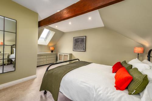 a bedroom with a white bed with red and green pillows at Luxury town centre loft apartment in converted Granary in Stamford