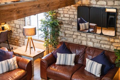 a living room with two leather couches and a mirror at Luxury town centre loft apartment in converted Granary in Stamford
