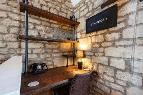 a stone walled room with a wooden desk with a lamp at Luxury town centre loft apartment in converted Granary in Stamford