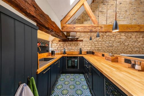 a kitchen with blue cabinets and a brick wall at Luxury town centre loft apartment in converted Granary in Stamford