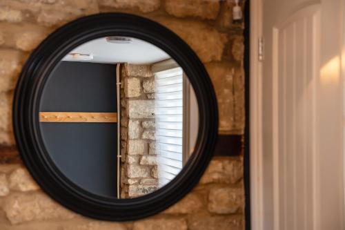 a black mirror on a brick wall with a window at Luxury town centre loft apartment in converted Granary in Stamford