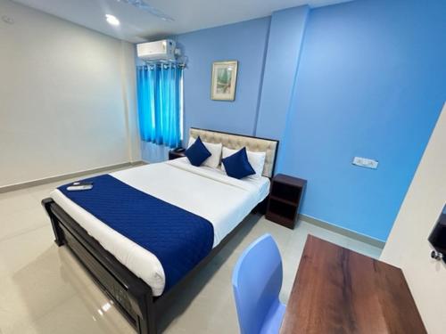 Un dormitorio con una cama con paredes azules y una mesa de madera. en Hotel Prime Classic, en Shamshabad