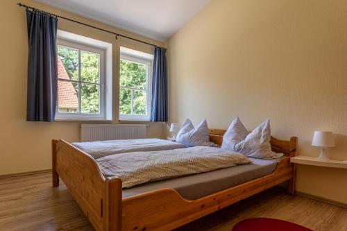 a bedroom with a wooden bed with two windows at Pension Cohrs Hof in Hellwege