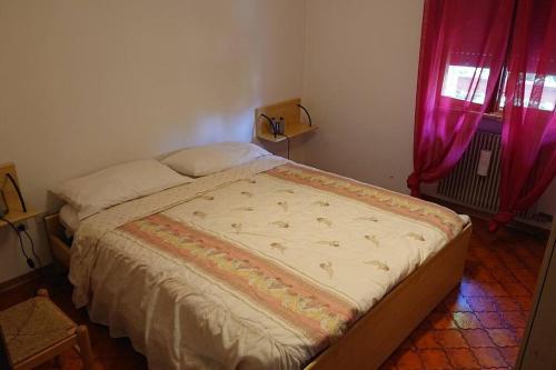 a bed in a bedroom with a red window at A due passi da Asiago... in Cesuna