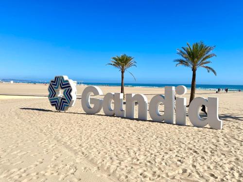 een bord op een strand met twee palmbomen bij Apartamento TalaMar Gandia Playa in Playa de Gandia