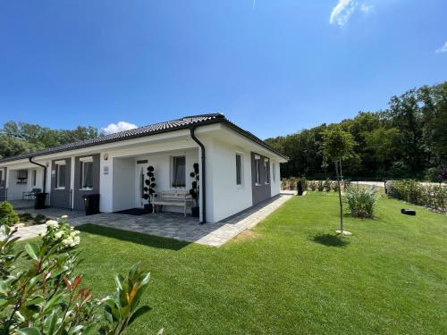 a small white house with a large yard at Jázmin Apartman in Sárvár