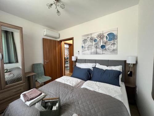 1 dormitorio con 1 cama grande con almohadas azules en Jázmin Apartman en Sárvár