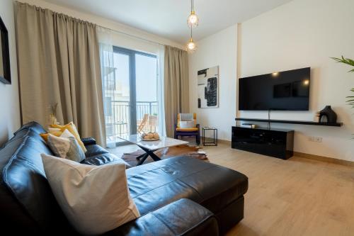 a living room with a couch and a flat screen tv at HiGuests - Stylish Waterfront Retreat With Balcony in La Mer in Dubai