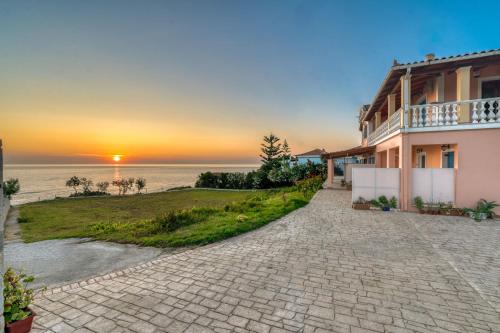 a house with a view of the ocean at sunset at St. Harry's Windmill in Makris Gialos