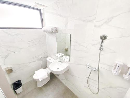 a white bathroom with a shower and a sink at Lun Hotel Manado in Manado
