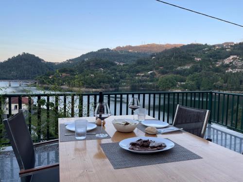 a wooden table with a plate of food and wine glasses at Estrela do Geres in Geres