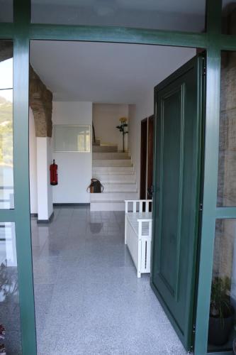a hallway with a green door and stairs in a building at Estrela do Geres in Geres