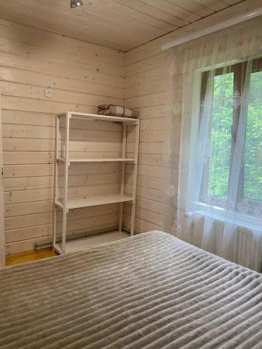 a bedroom with a bed and a shelf and a window at Карпатська Модрина in Kosiv