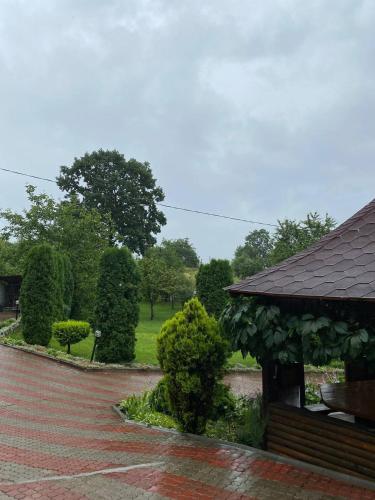 a brick walkway next to a building with bushes and trees at Карпатська Модрина in Kosiv