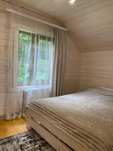 a bedroom with a bed and a window at Карпатська Модрина in Kosiv