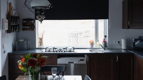 a kitchen with a sink and a window and a table at Kamburinn Cottage in Hveragerði