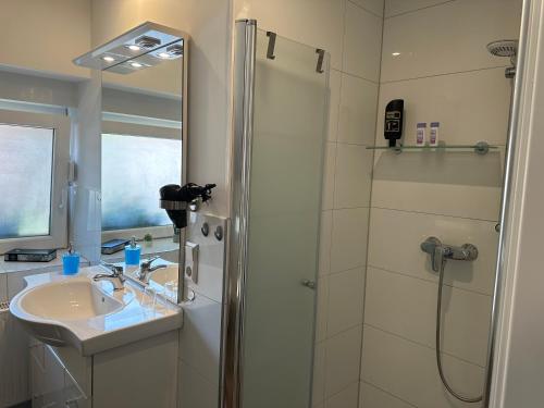 een witte badkamer met een douche en een wastafel bij Ferienwohnung Bispingen in Bispingen
