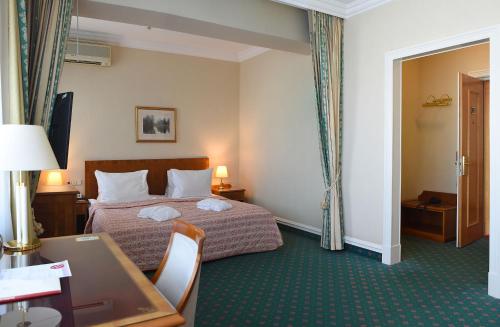 a hotel room with a bed and a desk and a table at Natsionalny Hotel in Kyiv