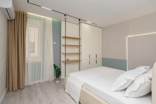 - une chambre avec un grand lit blanc et une fenêtre dans l'établissement Marina Luxury Apartments Durrës, à Durrës