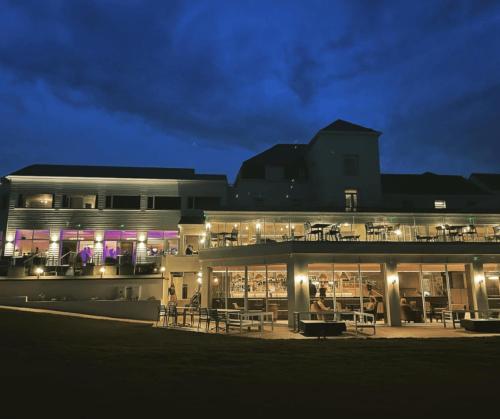 un grande edificio con tavoli e sedie di notte di The Cliff Hotel & Spa a Cardigan