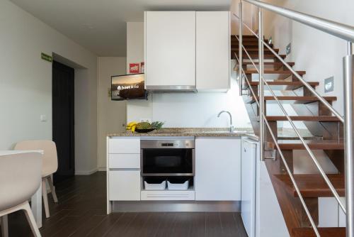 a kitchen with white cabinets and a spiral staircase at Host Wise - Impressive Restful Houses in Porto