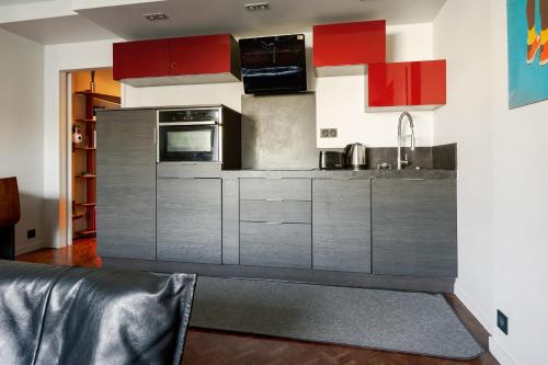 une cuisine avec des armoires en acier inoxydable et du rouge dans l'établissement Appartement Folie-Méricourt - Welkeys, à Paris