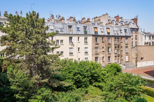 un immeuble à Paris avec un arbre au premier plan dans l'établissement Appartement Folie-Méricourt - Welkeys, à Paris
