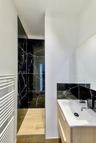 une salle de bain avec un lavabo et une douche avec un miroir dans l'établissement L'horizon, à Saint-Étienne