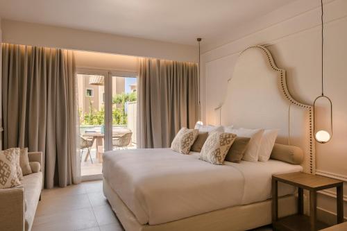 Thalassa Boutique Hotel - Adults Only في لاسي: غرفة نوم بسرير ابيض كبير وبلكونة