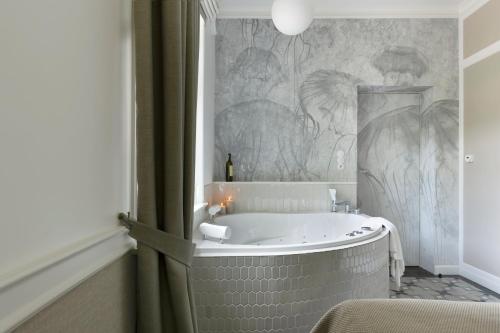 a bath tub in a bathroom with a mural at Willa Szwarc by Elite Apartments in Sopot