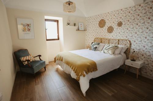 a bedroom with a large bed and a chair at Apartamento Baluarte de los Pozos in Cáceres
