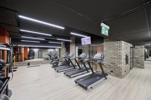 a gym with a row of treadmills and machines at Walońska 16 Sauna & Fitness Family Apartments by Renters Prestige in Wrocław