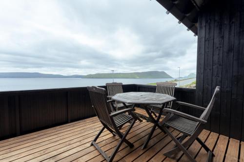 einen Tisch und Stühle auf einer Terrasse mit Blick auf das Wasser in der Unterkunft Nordic Serenity - Amazing Sea And Mountain View 