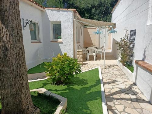 une cour avec une table, des chaises et un arbre dans l'établissement MARTIGUES Adorable petite guest house, à Martigues