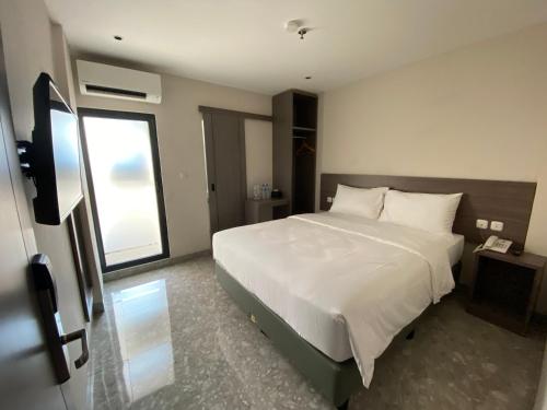 a bedroom with a large white bed and a window at Lun Hotel Manado in Manado