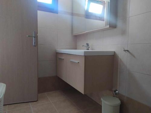 uma casa de banho com um lavatório, um espelho e um WC. em Garden House KRISTI em Kalandra
