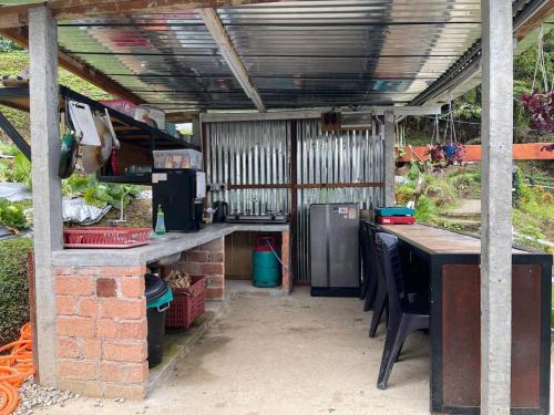 an outdoor kitchen with a table and a refrigerator at The Backyard Glamping Cameron Highlands in Tanah Rata