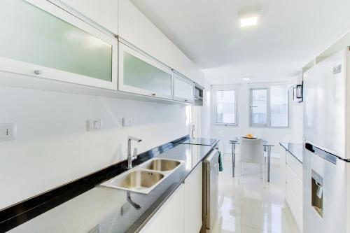 uma cozinha com armários brancos e um lavatório em Oceana Suites en Isabel, frente a playa Mansa em Punta del Este