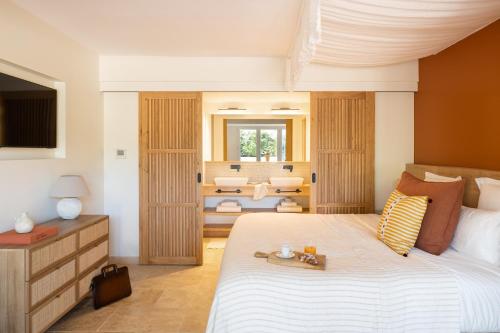 a bedroom with a large bed and a living room at Hôtel L'Escalet in Ramatuelle