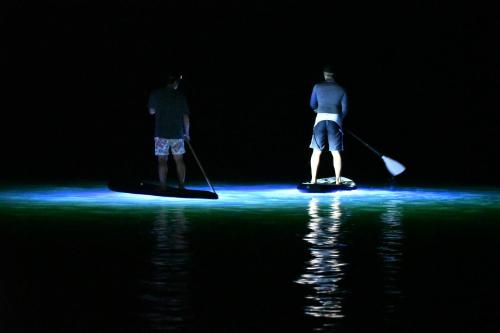two people are standing on paddle boards in the water at Shiga Kogen Olympic Hotel in Yamanouchi