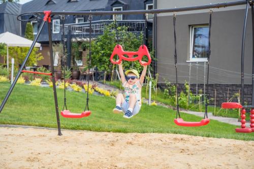 a young child is swinging on a swing at Srebrny Bucznik Wellness & Restaurant in Istebna