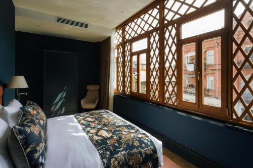 a bedroom with a bed and two windows at Puris Moedani Boutique Hotel in Tbilisi City