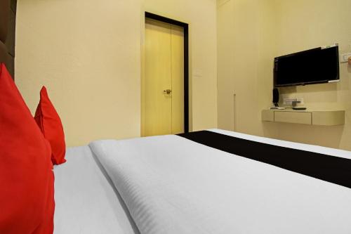 a bedroom with a white bed with red pillows and a television at Super Collection O Snowfox in Kolkata