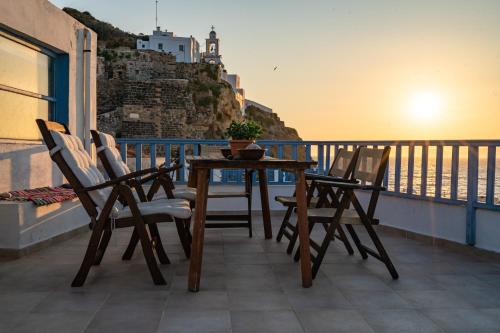 a table and chairs on a balcony with a view of the ocean at Imerios Nisyrian House in Mandrákion