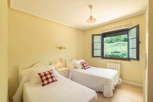 a bedroom with two beds and a window at Casa La venta de Pedro in Ribadesella