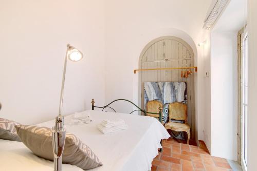 um quarto branco com uma cama e um candeeiro em Casa Rosa em São Brás de Alportel
