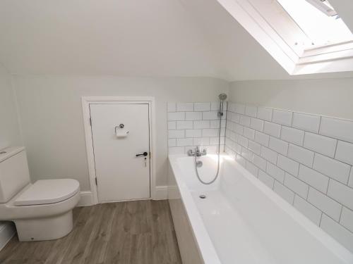 a white bathroom with a toilet and a bath tub at Chine Heights in Bournemouth