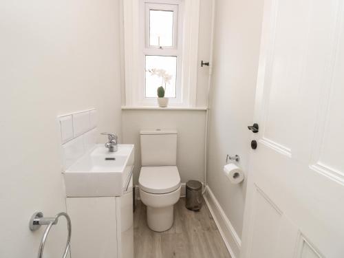 a white bathroom with a toilet and a sink at Chine Heights in Bournemouth