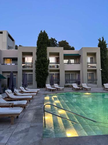 a hotel with a swimming pool and lounge chairs at Ambrosia Hotel Beach & Spa in Bitez